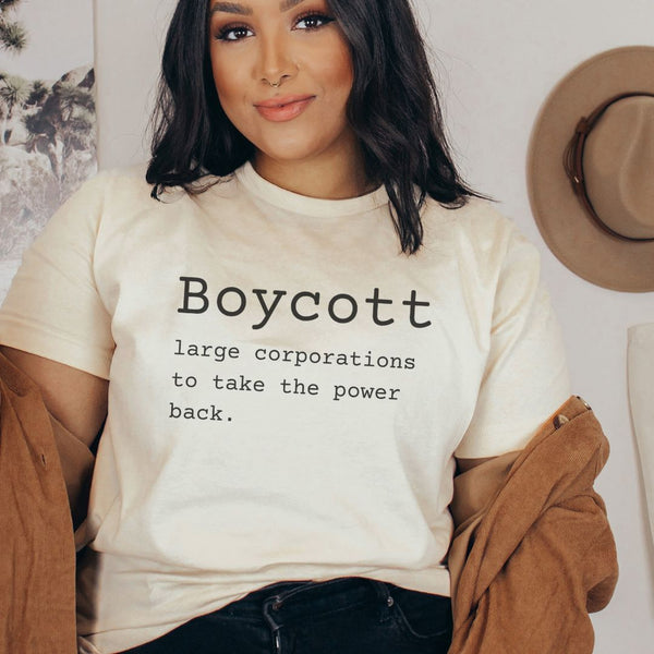 girl wearing tan shirt with typewriter font that says "Boycott large corporations to take the power back."